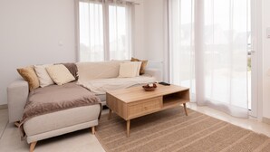 Una sala de estar moderna con un sofá, una mesa de centro y ventanas amplias.