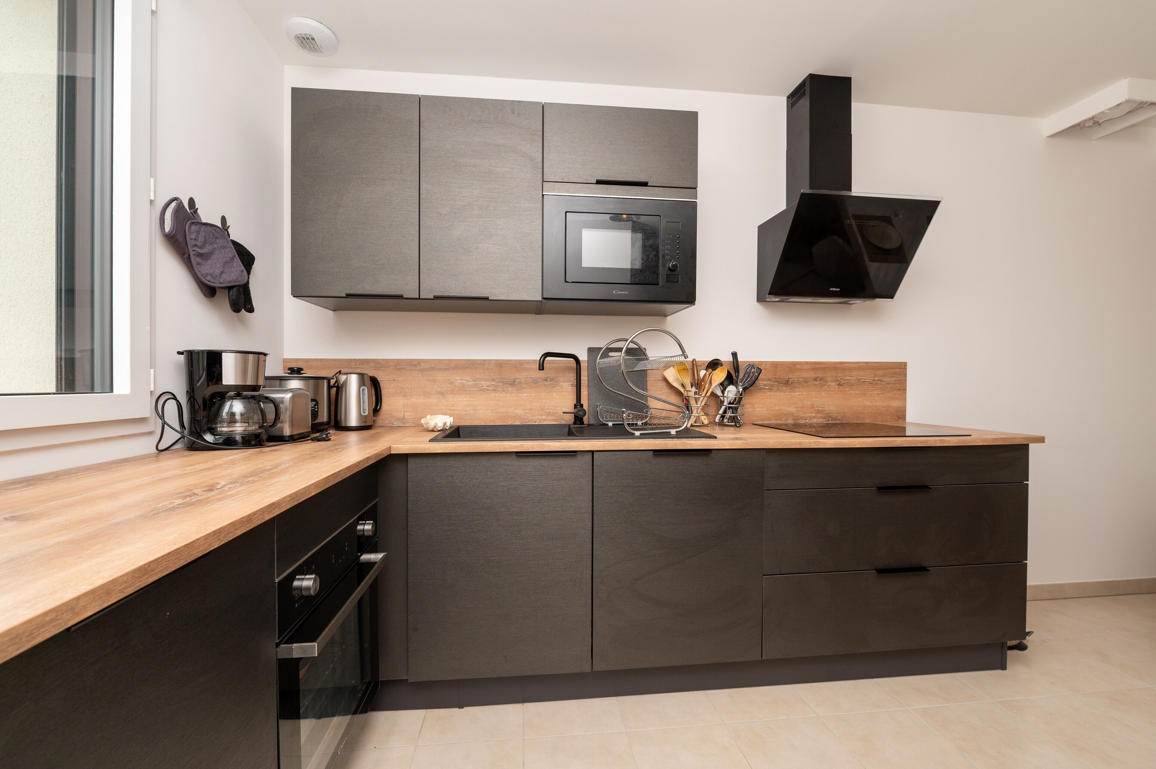 A modern kitchen with dark cabinetry, a stainless steel microwave, a coffee maker, and a sink.