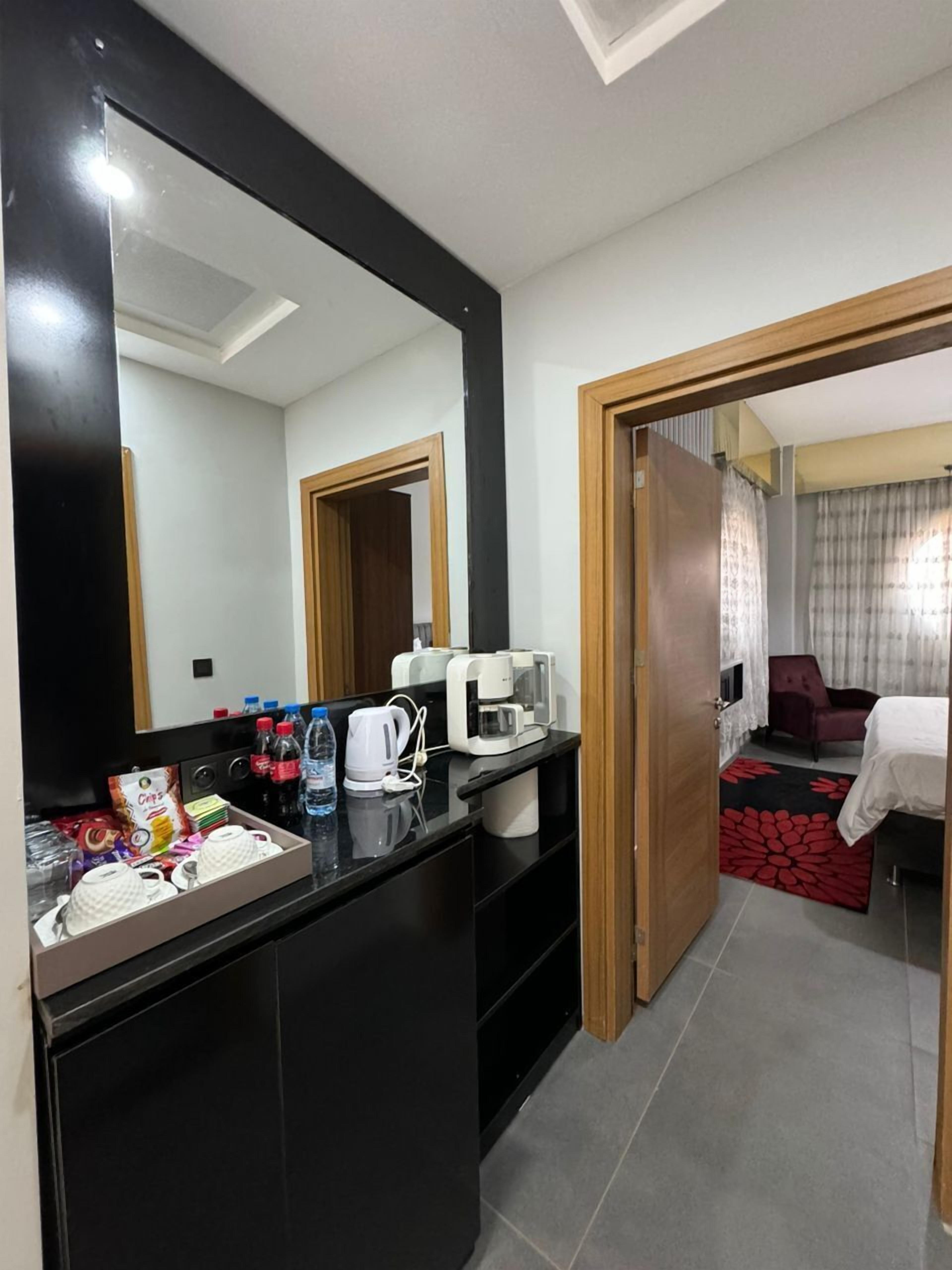 A hotel room with a black minibar, a coffee maker, and a red floral rug.