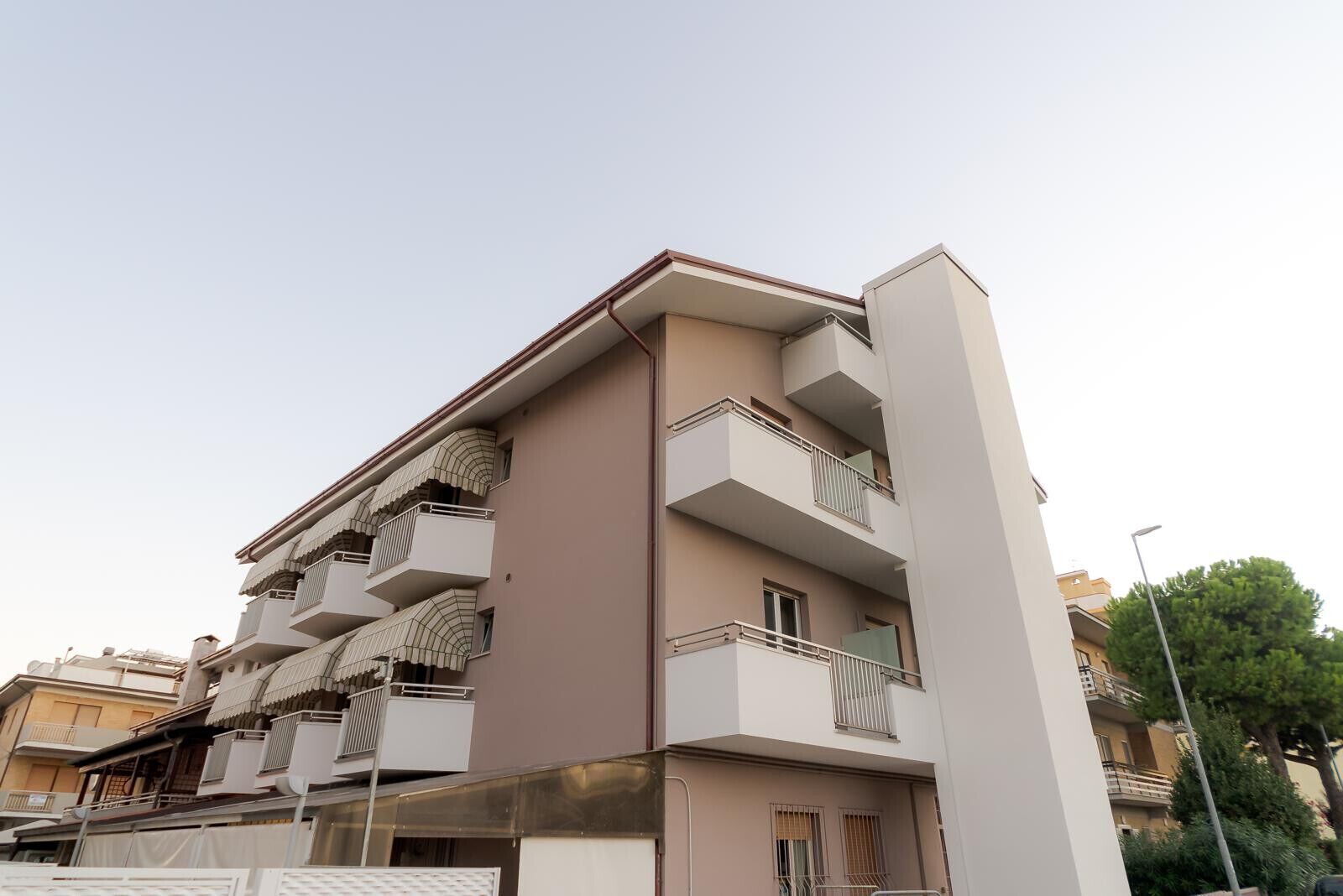 Un edificio residencial de varios pisos, con balcones, techo plano y fachada color beige.