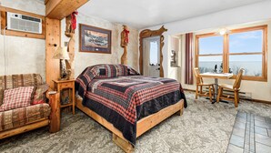 A cozy bedroom with a wooden bed, a small table, and a chair. There is a window with a view of the outdoors. - Relaxing Getaway Surrounded by Nature & Beauty (Duluth)