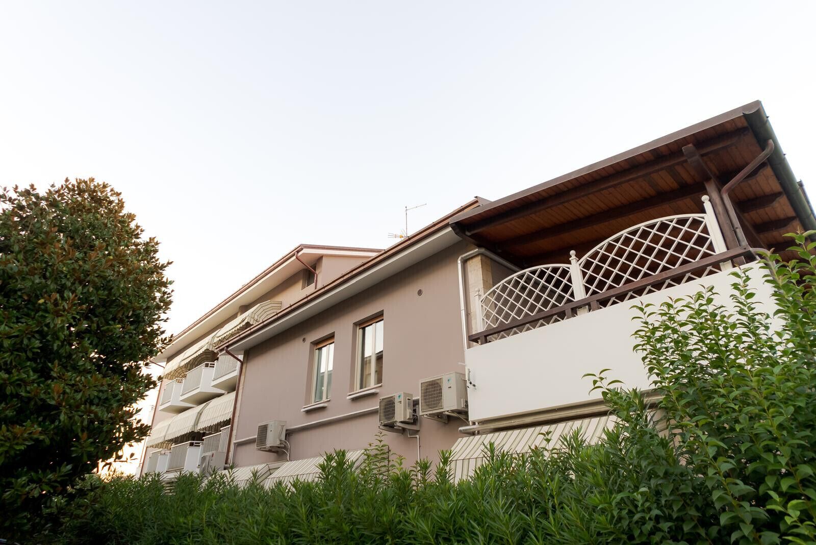 A two-story building with a balcony and air conditioning units.