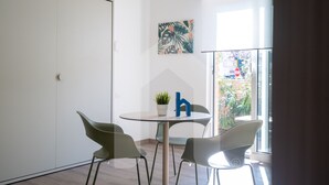 Een moderne kamer met een glazen deur, een ronde tafel met twee stoelen, een potplant en een kunstwerk aan de muur.