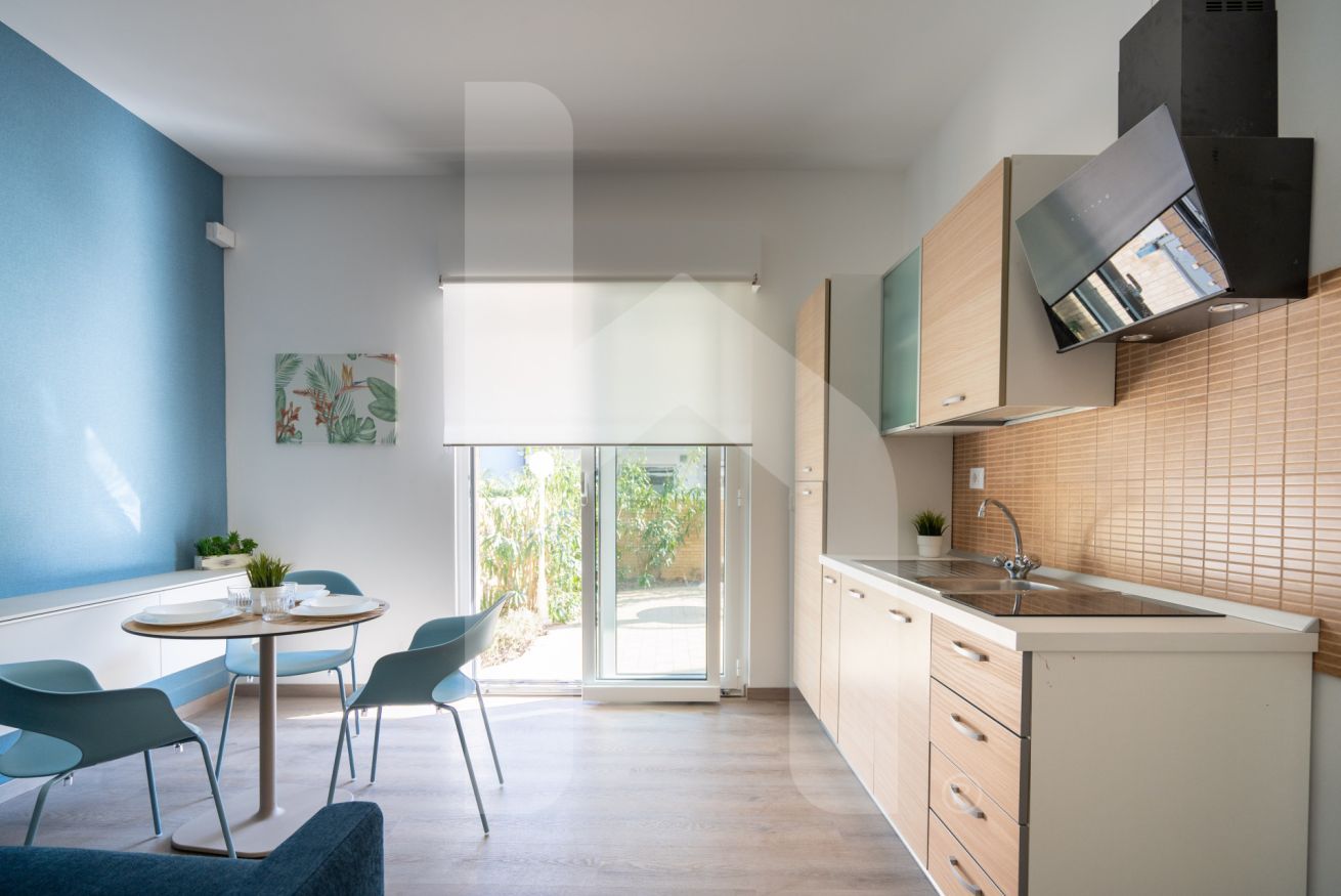 A modern kitchen with a built-in oven, a sink, and a window overlooking a garden.