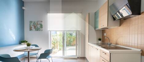 A modern kitchen with a built-in oven, a sink, and a window overlooking a garden.