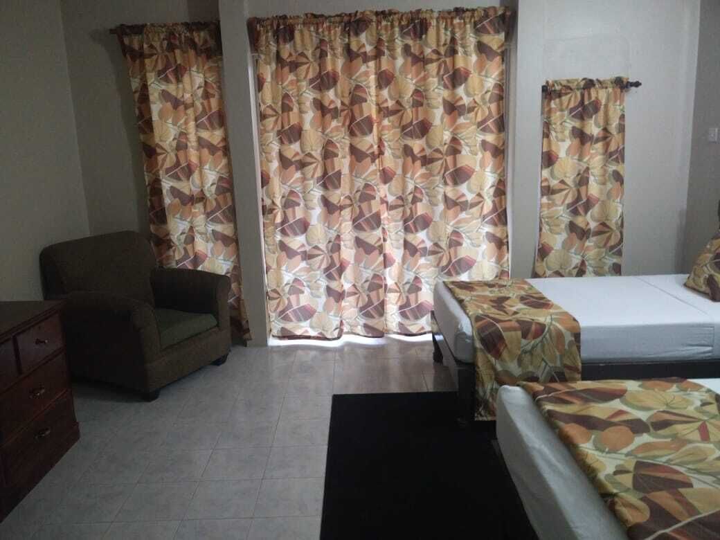 A room with a bed, a chair, a dresser, and curtains.
