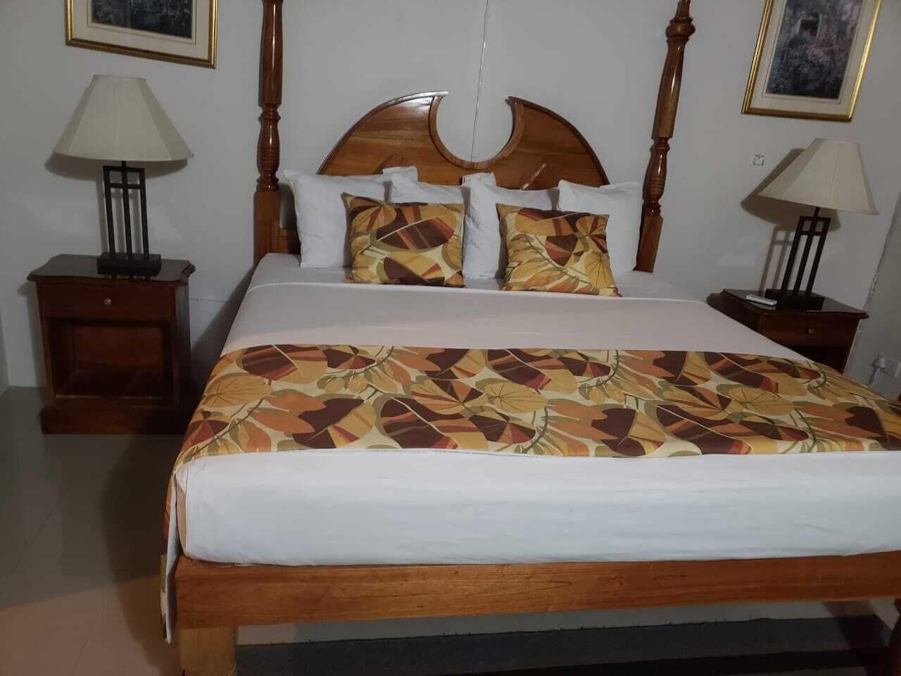 A bed with a wooden headboard, two bedside tables with lamps, and a patterned bedspread.