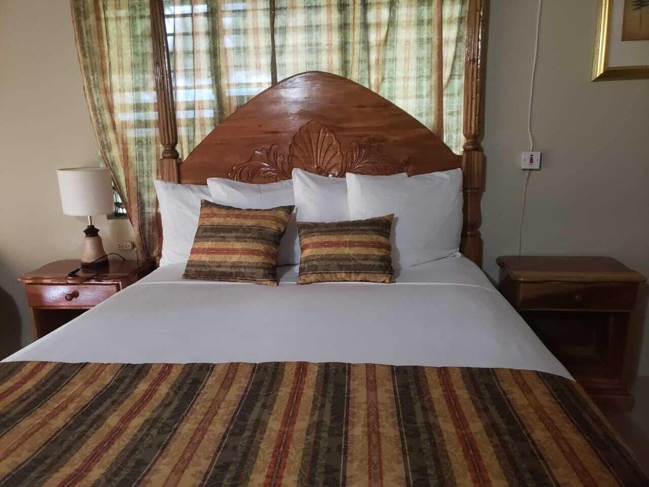 Un lit bien fait, avec une couvre-lit à rayures, deux oreillers et une tête de lit en bois.