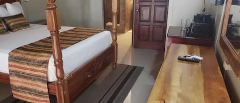 A bedroom with a four-poster bed, a wooden nightstand, and a mirror.