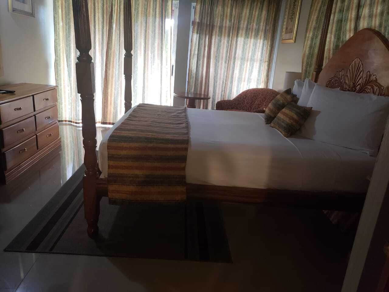 Une chambre à coucher avec un lit en bois, une table de chevet, une commode et des rideaux.
