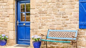 A stone building with a blue door and a bench in front.