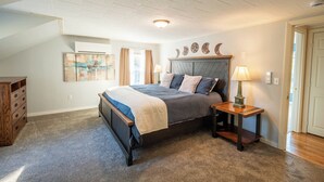 A bedroom with a bed, a nightstand, a dresser, and a ceiling fan.