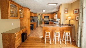 A kitchen with wooden cabinets, a granite countertop, and a bar area with stools.