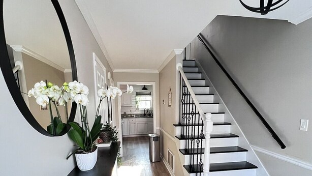 Una escalera moderna con diseño blanco y negro que conduce a una zona de cocina.