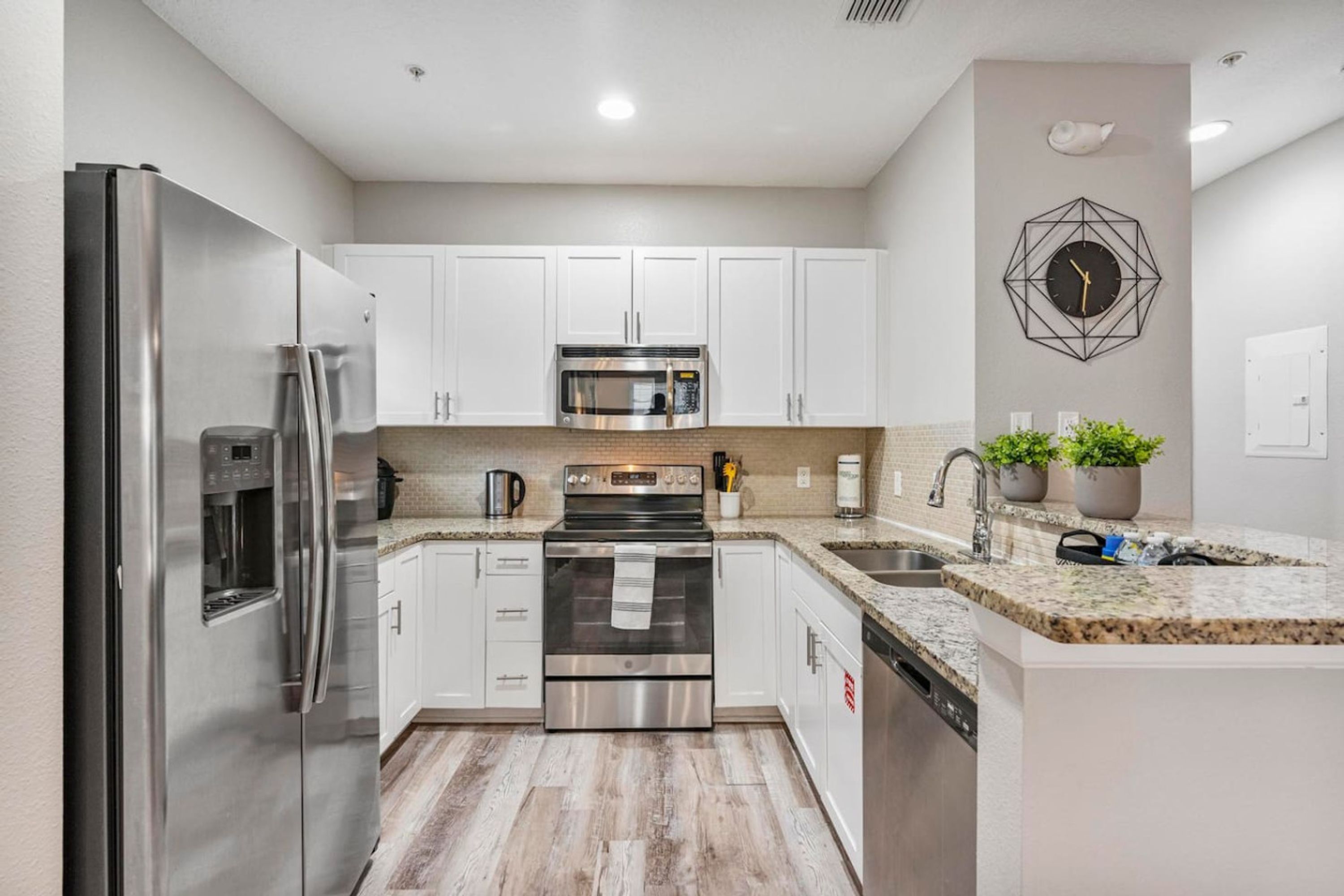A modern kitchen with stainless steel appliances, white cabinets, and a granite countertop.