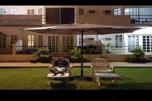 A hotel with outdoor seating under a large umbrella, a building with a sign reading 'The Ocean Bohol,' and a well-maintained lawn. - Blue Ocean Bohol Beachfront (Panglao Municipality)