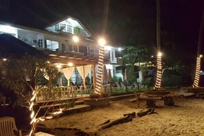 A beachfront property with a covered outdoor seating area, a sandy beach, and a building with multiple levels. - Blue Ocean Bohol Beachfront (Panglao Municipality)