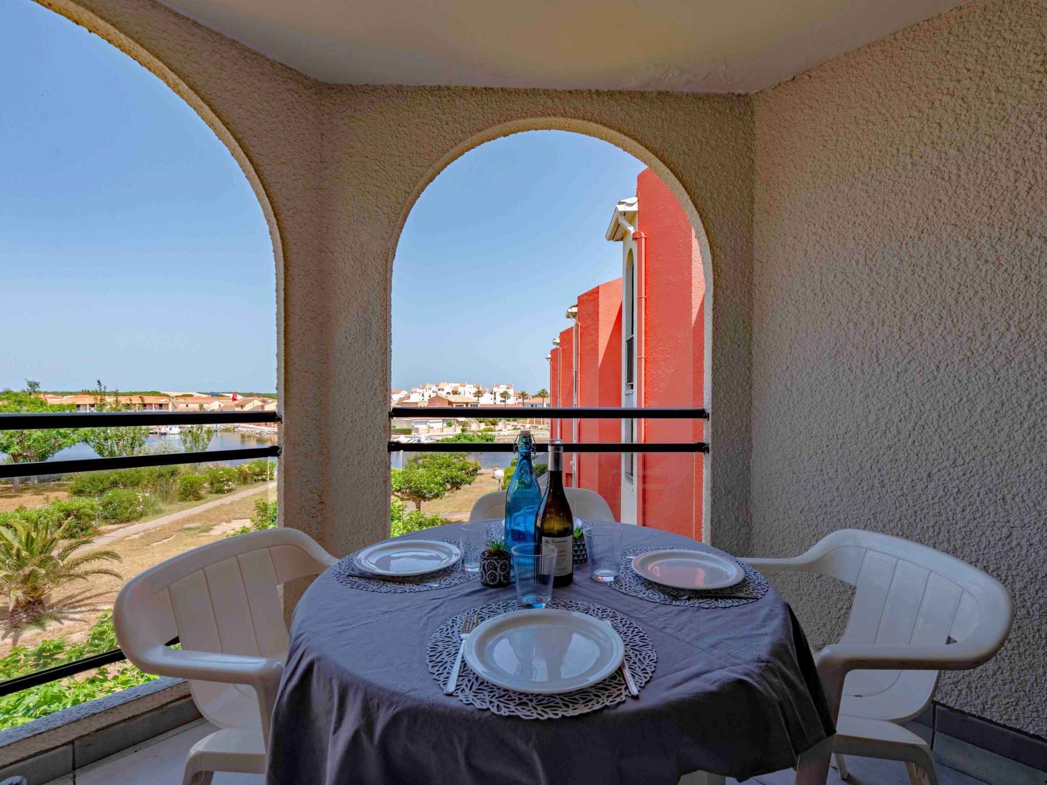 A balcony with a table set for two, overlooking a coastal view.