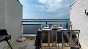 A balcony with a table set for two, overlooking a body of water. - Les Marquises by Interhome (Le Barcarès)