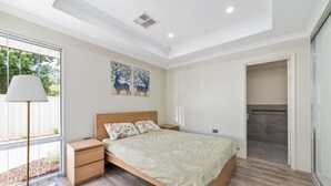 Un dormitorio moderno con cama de madera, mesitas de noche y un ventanal grande.