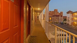 A corridor with a red door marked '220', a balcony with a railing, and a view of buildings in the background. - The Ward - Resort Style Gameday Condo (Tallahassee)