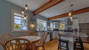 A modern kitchen with wooden chairs, a dining table, and a large island with stools.