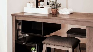 Une salle de bain moderne avec un meuble-lavabo en bois, un évier, un miroir, un luminaire suspendu, une serviette et une petite plante en pot.