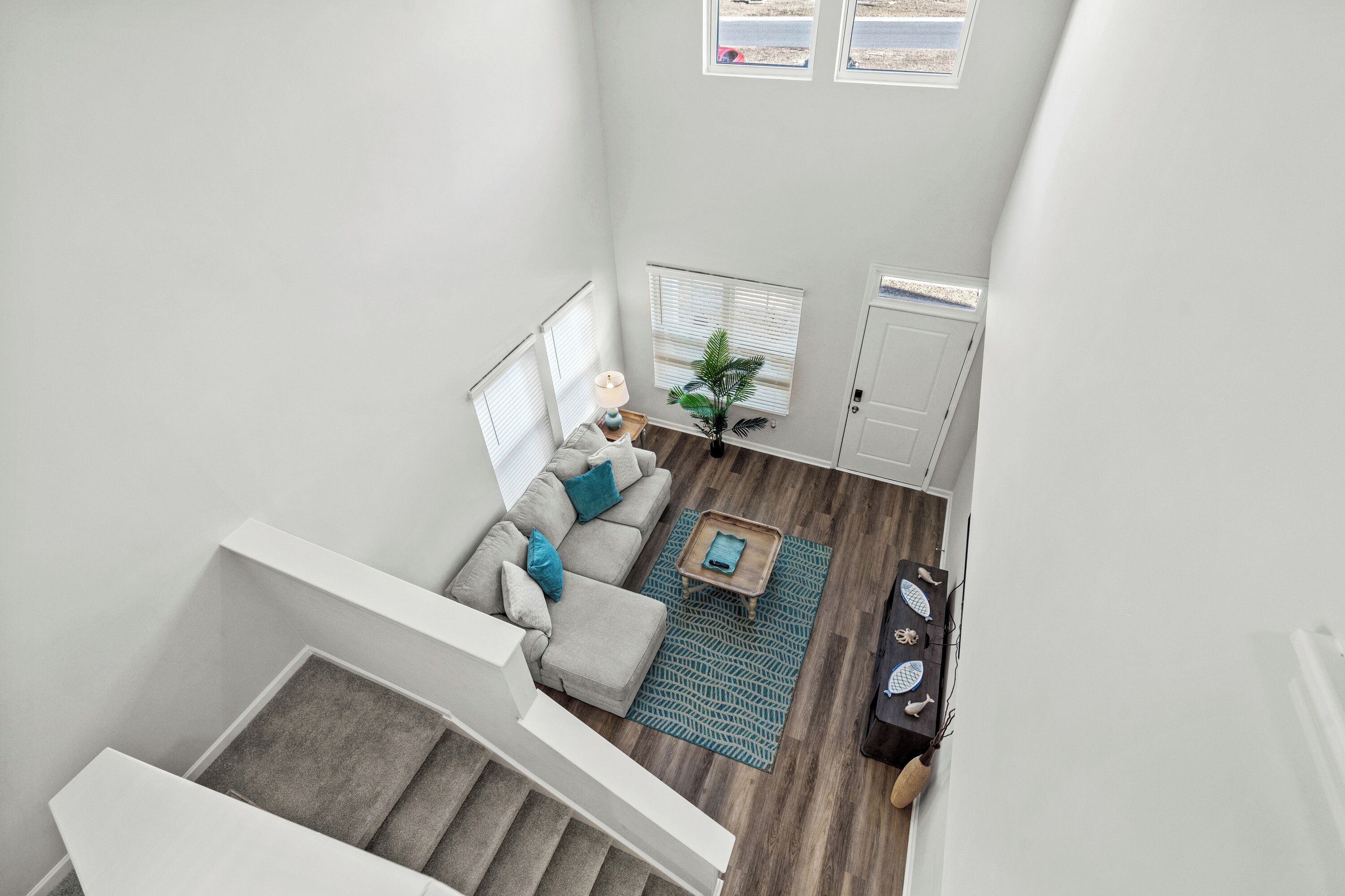 A spacious living area with a staircase, a sofa, a coffee table, and a plant.