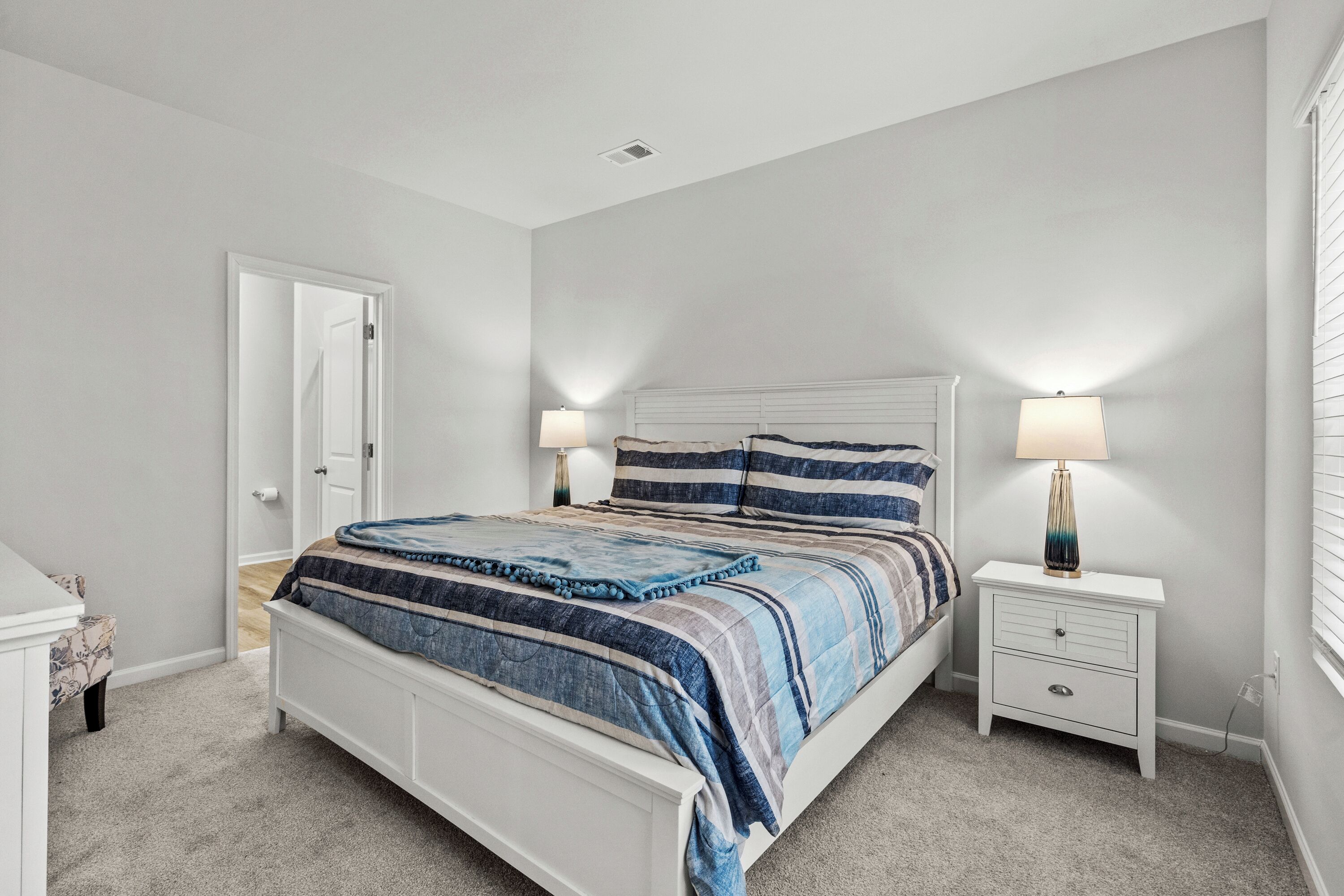 A bedroom with a bed, bedside tables, a nightstand, and a door.