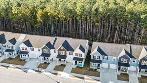 A row of modern, two-story houses with a uniform architectural style, featuring gabled roofs and a central driveway. - 3-bedroom townhome in amazing Calabash next to Meadowlands Golf Course & Beach (Calabash)