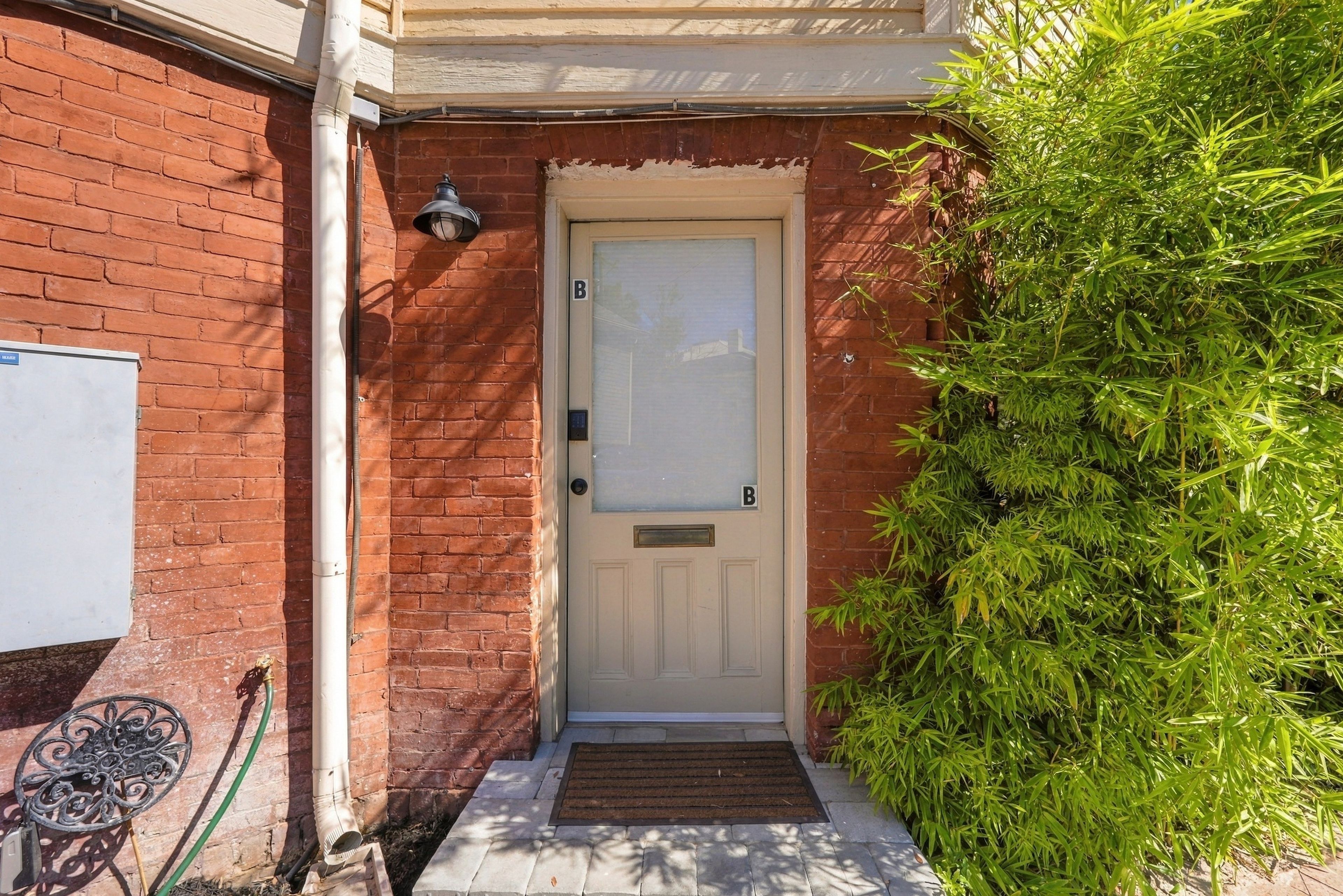 A white door with a mail slot, a small step leading to the entrance, and a metal mailbox to the left.