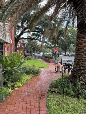 A brick pathway leading to a building with a statue, surrounded by lush greenery and palm trees. - Private studio/parking in historic mansion, close to forsyth park, dogs welcome (Savannah)