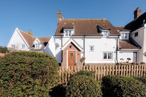 A row of white houses with brown tiled roofs, a wooden fence, and dense green foliage in the foreground. - 3 Barley Lands, Aldeburgh (Aldeburgh)