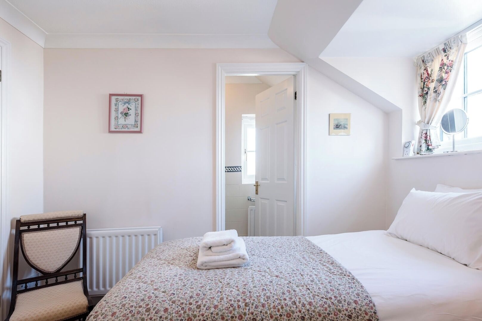 A bedroom with a bed, a chair, a radiator, and a door leading to another room.