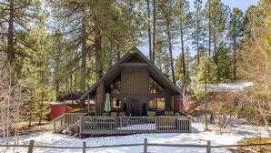 A cabin with a porch, surrounded by trees and snow.