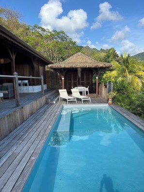 Relax by the serene pool surrounded by lush vegetation and comfortable lounge chairs.