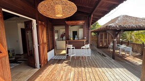 Relax on the deck with a casual dining or sitting area, featuring a thatched-roof structure and wooden planks.