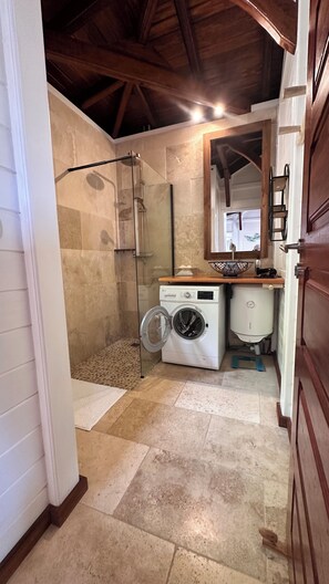 Laundry room with a glass-enclosed shower, washing machine, and dryer.