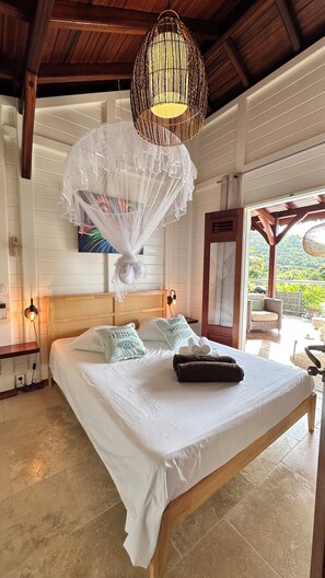 Relax in a serene bedroom with a large bed, a unique canopy, and a balcony offering views of lush greenery.