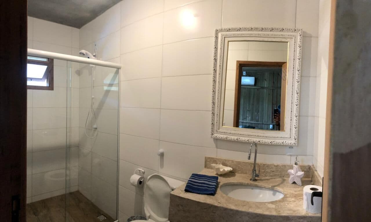 Een badkamer met een douchecabine van glas, een wastafel met een marmeren blad en een spiegel met een decoratieve lijst.