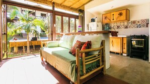 A room with a wooden bed, a kitchen area, and a view of the outdoors. - Pousada guarda beach house (Palhoca)