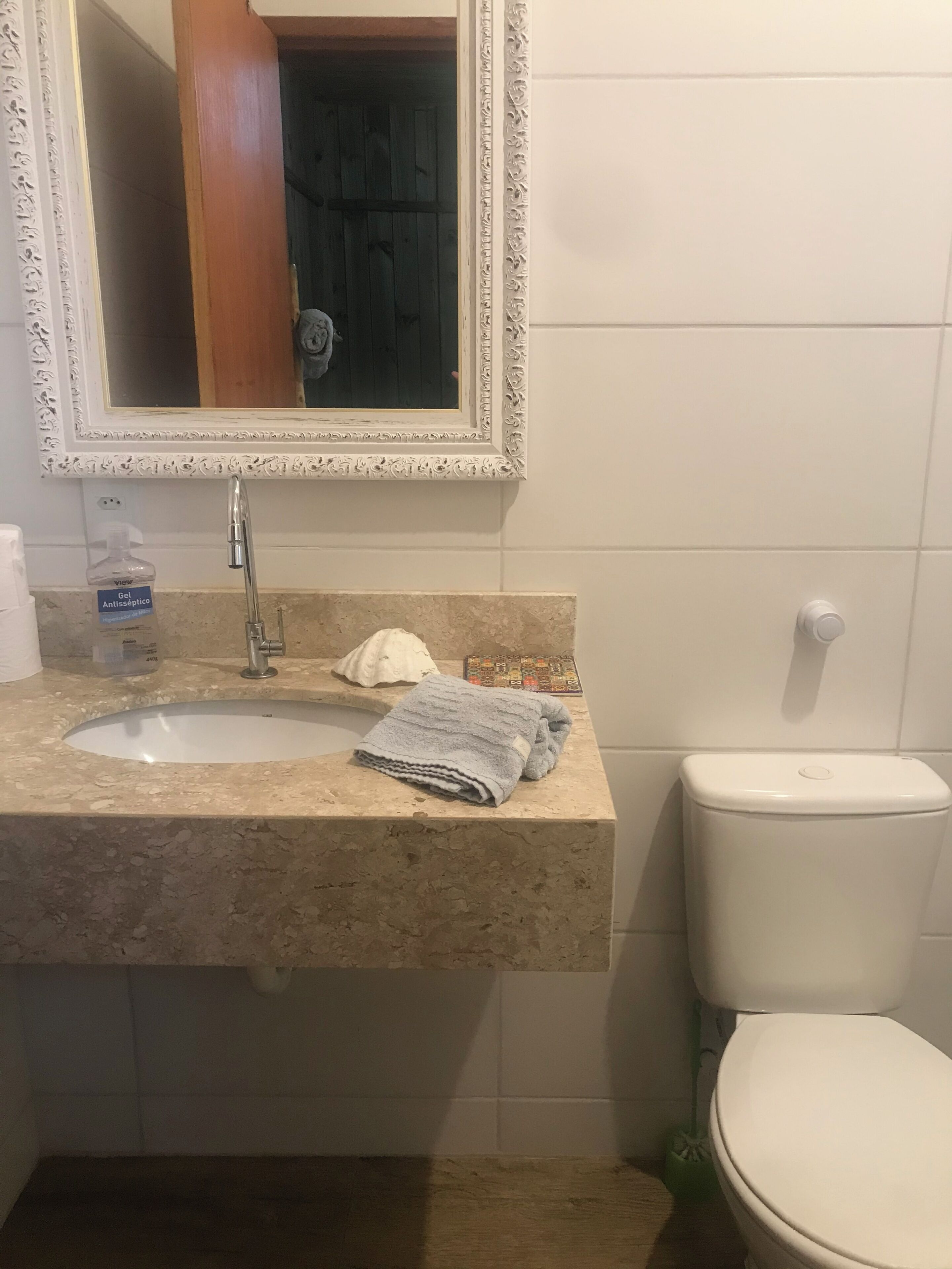 Un baño con lavabo, espejo, inodoro y una toalla sobre la encimera.