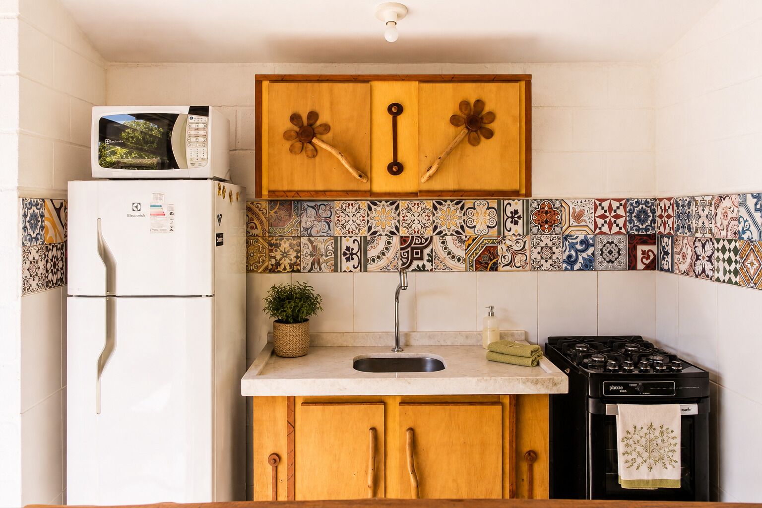 A compact kitchen with a white refrigerator, wooden cabinets, a sink, and a stove.