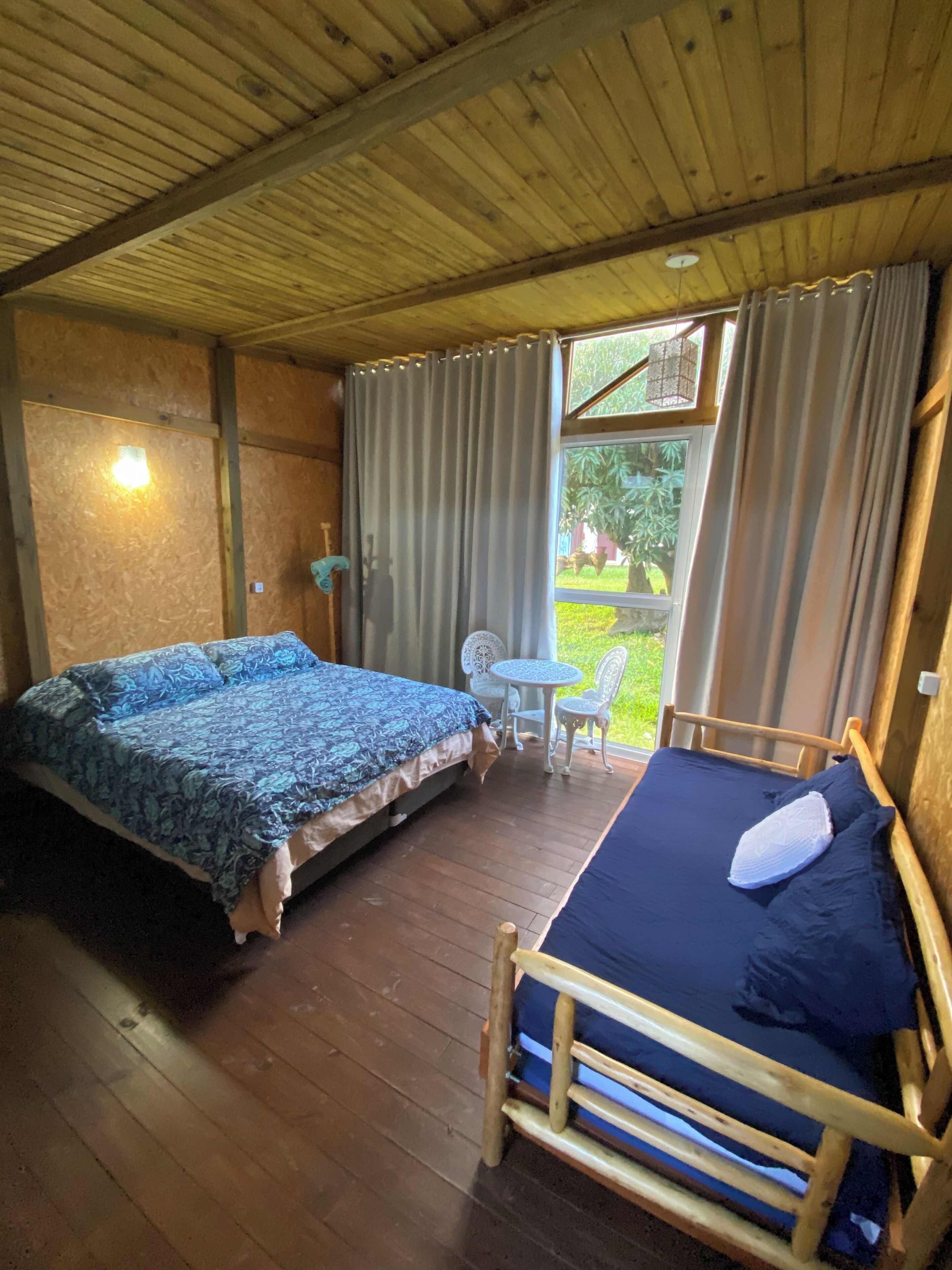 A room with two wooden beds, a small table, and a chair.