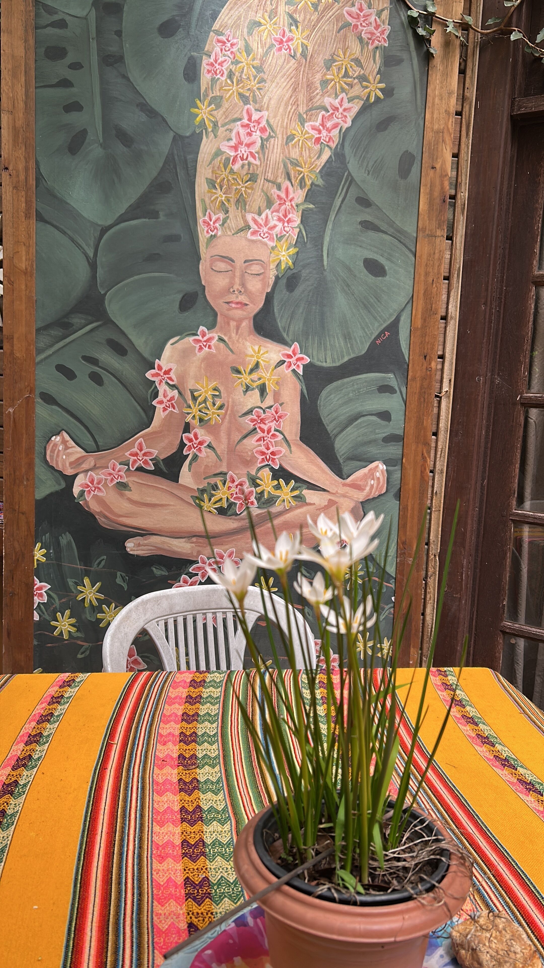 A potted plant on a colorful striped tablecloth with a mural in the background.