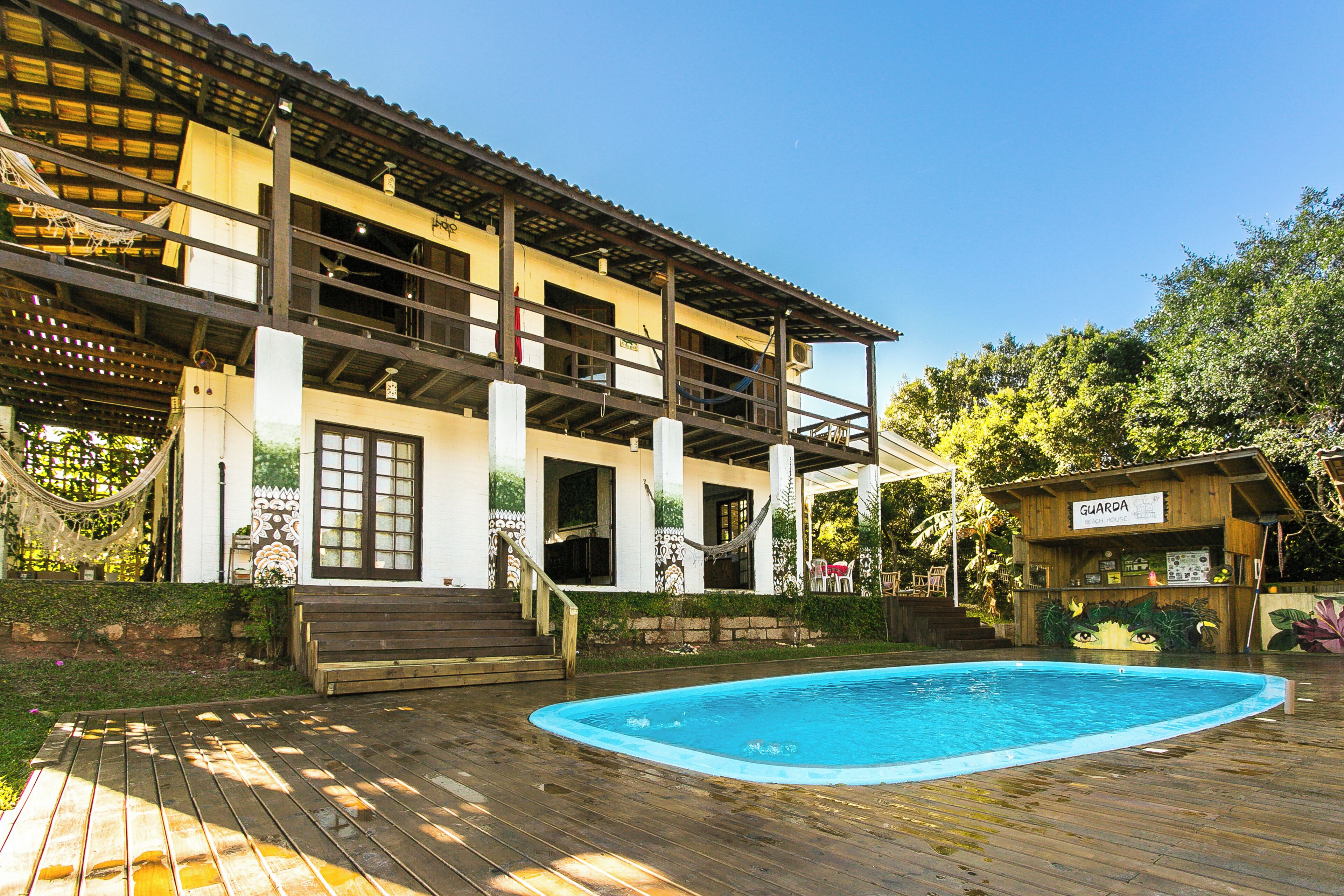 A two-story building with a pool, wooden deck, and a beach house labeled 'GUARDIA BEACH HOUSE'.