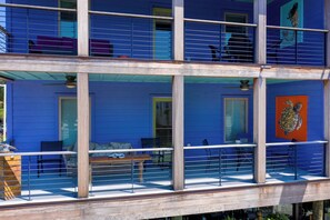 A multi-story building with a balcony, outdoor seating, and a large window.