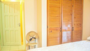 A bedroom with a bed, a wooden wardrobe, a door, and a hat on a stool. - A Trini Paradise - 4 bedroom apartment with WiFi, AC in enjoyable Tunapuna (Tunapuna)