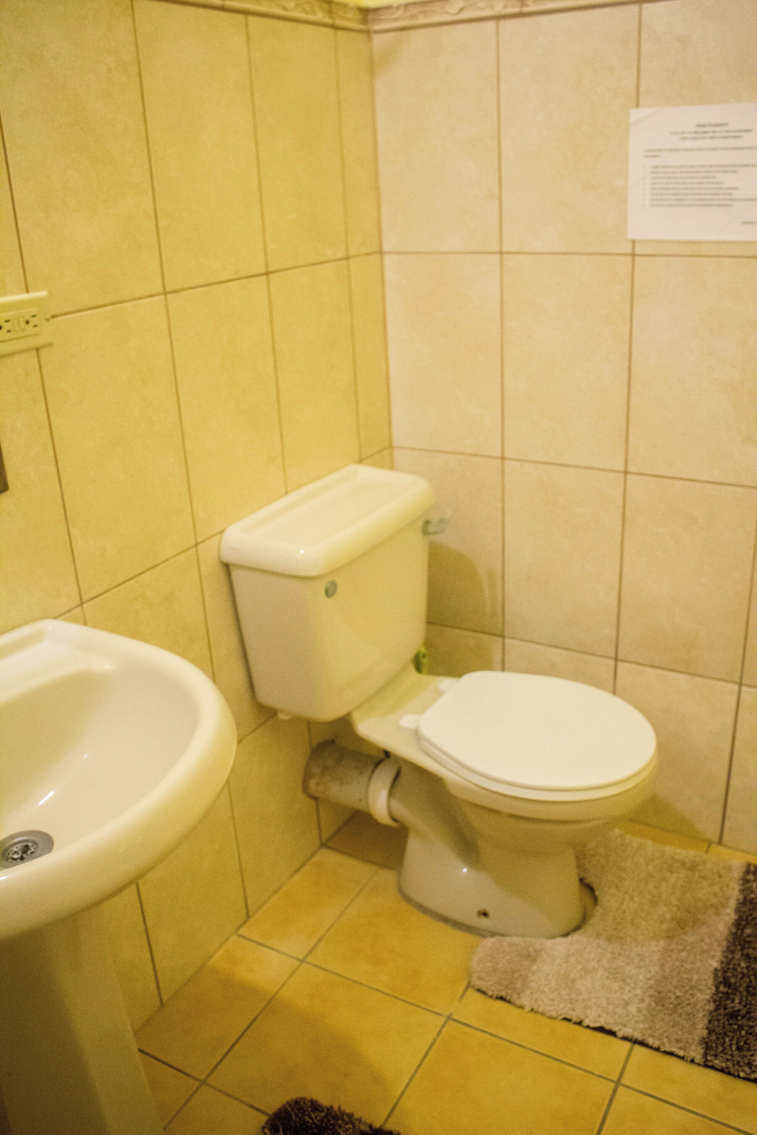 A bathroom with a toilet, sink, and a tiled floor.