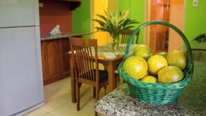A kitchen with a refrigerator, wooden cabinets, a dining table with chairs, and a basket of lemons on a granite countertop. - A Trini Paradise - 4 bedroom apartment with WiFi, AC in enjoyable Tunapuna (Tunapuna)